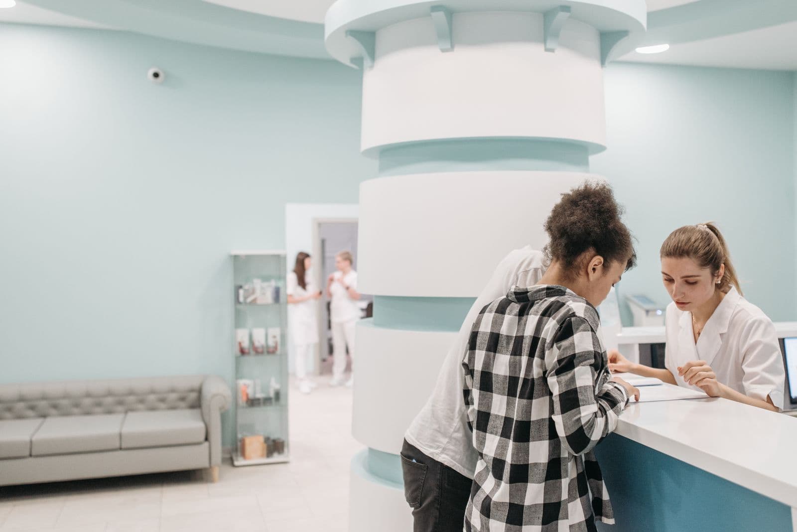 Personal sanitario atendiendo a un paciente en el mostrador de recepción de una clínica moderna.