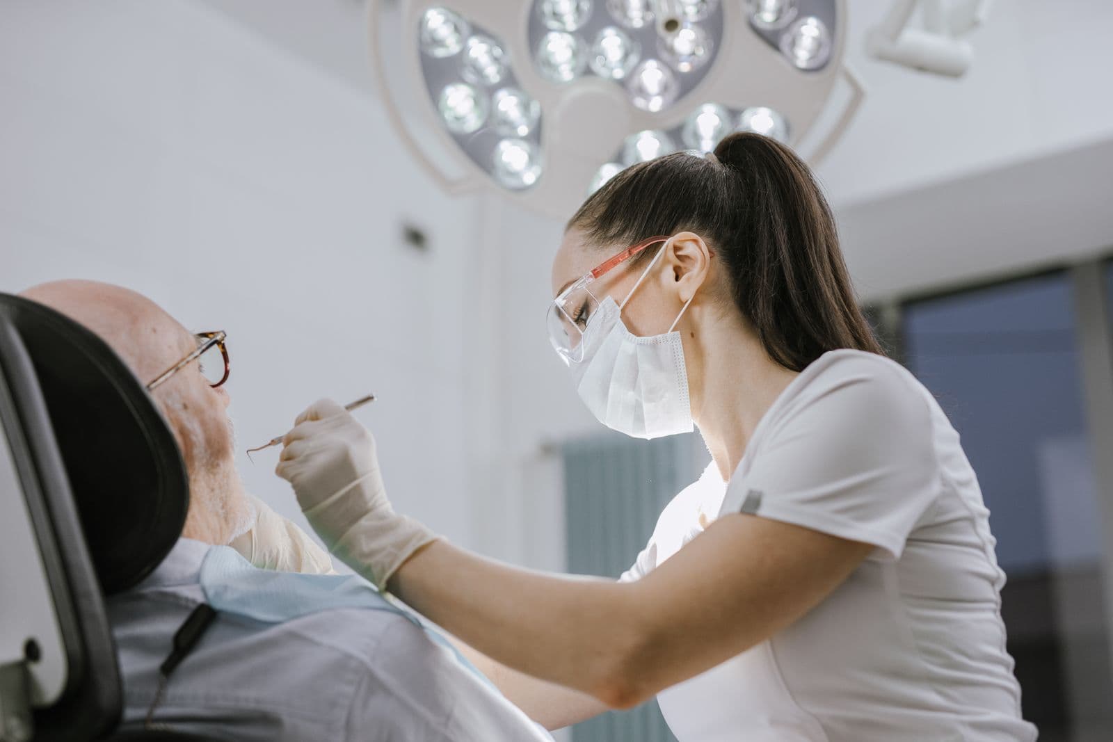 Dentista examinando a un paciente sentado en el sillón de una clínica dental moderna.